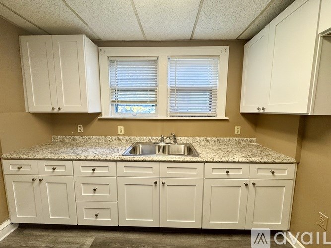 A kitchen with white cabinets and a granite countertop.