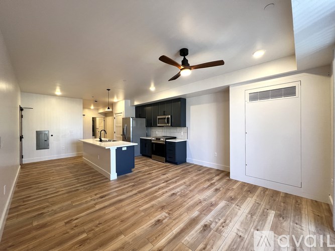 A spacious kitchen with wooden floors and a ceiling fan.