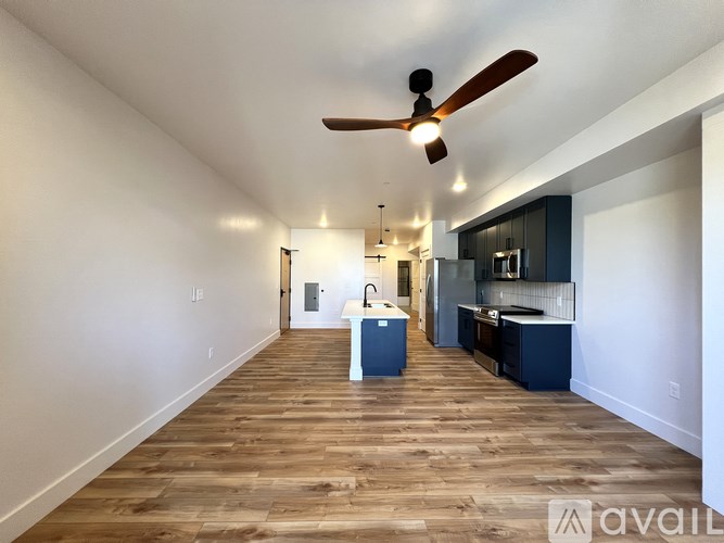 A spacious kitchen and living room with wooden floors and a ceiling fan.