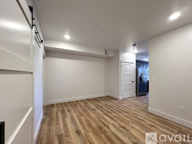 A room with wooden flooring and white walls, with a door on the right side.