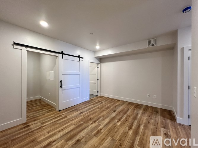 A room with wooden flooring and white walls, with a door and a mirror on the wall.
