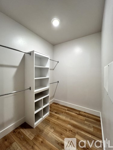 A white shelving unit in a room with wooden flooring.