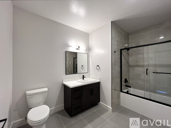 A bathroom with a toilet, sink, mirror, and shower.