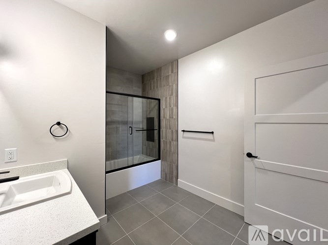 A bathroom with a white sink and a glass shower door.