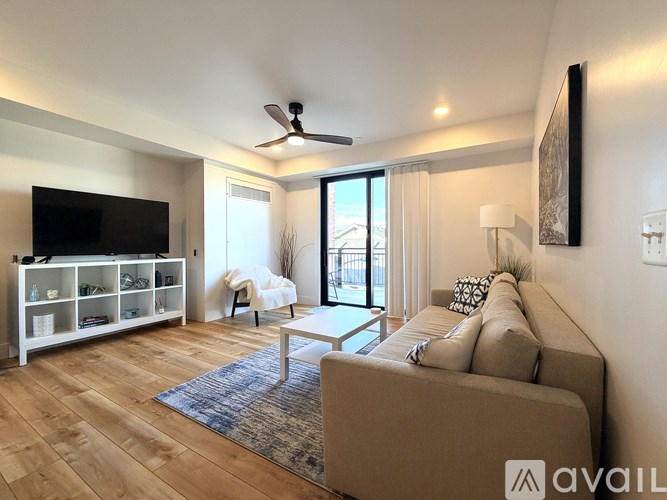 A living room with a couch, a television, a chair, and a rug.