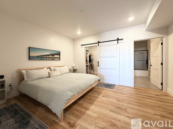 A bedroom with a bed, a painting, and a sliding door.