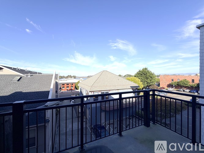 A balcony with a black railing and a view of the sky and buildings.