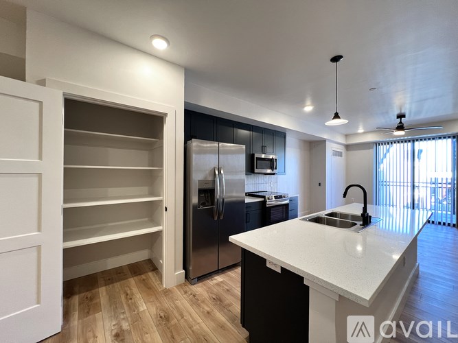 A modern kitchen with a white countertop and wooden flooring.