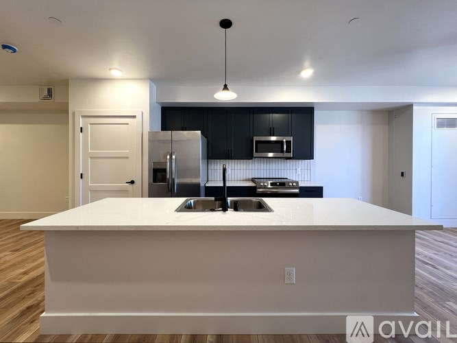 A modern kitchen with a white island and black cabinets.