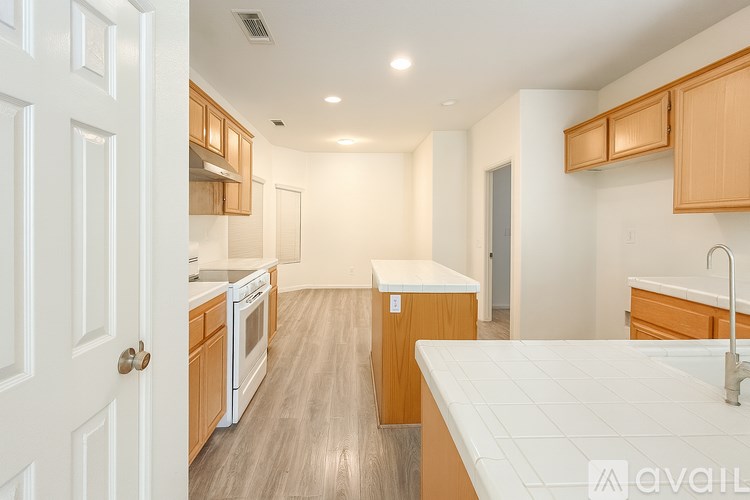 A kitchen with white countertops and wooden cabinets.