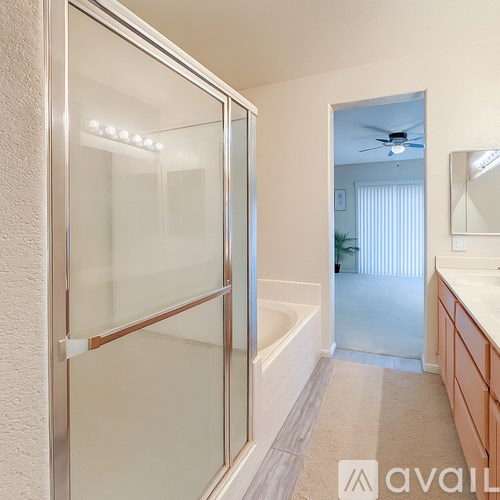A bathroom with a glass shower door and a white tub.