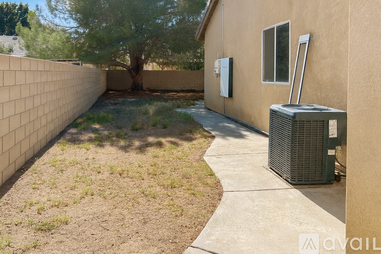 A backyard with a wall, a tree, and a heat pump.