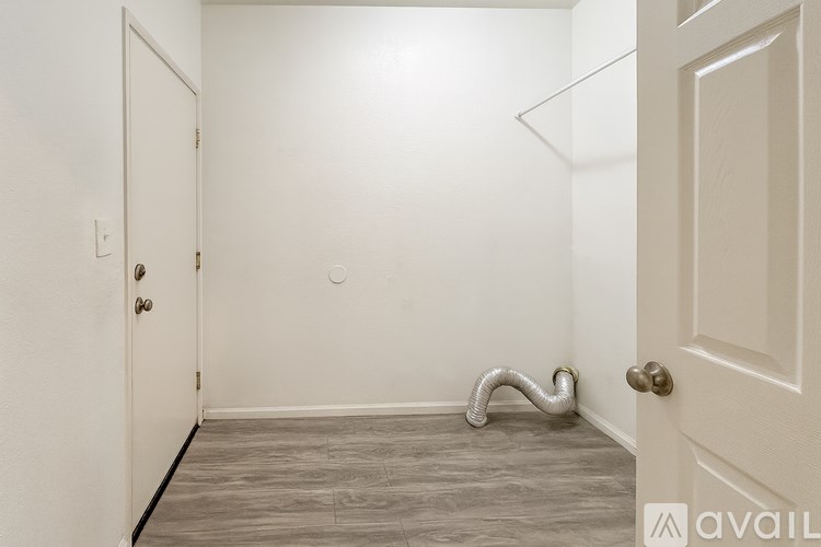 A room with a white door and a white wall with a silver snake on the floor.