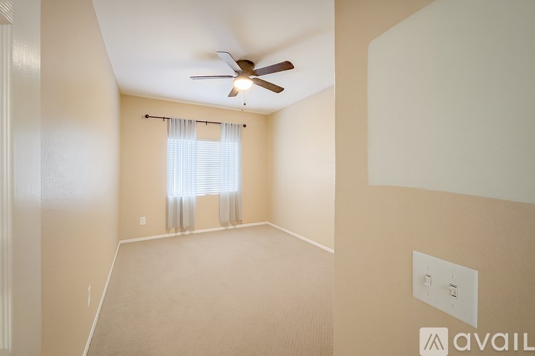 A room with a ceiling fan and a window with blinds.