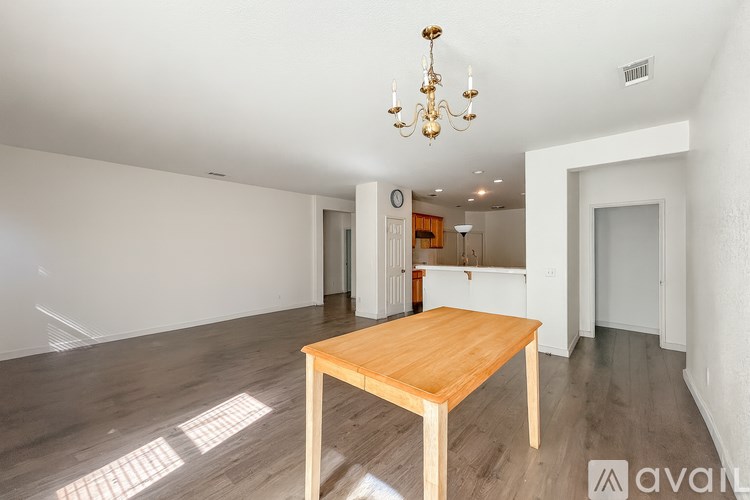 A wooden table is in the middle of a room with a chandelier hanging from the ceiling.