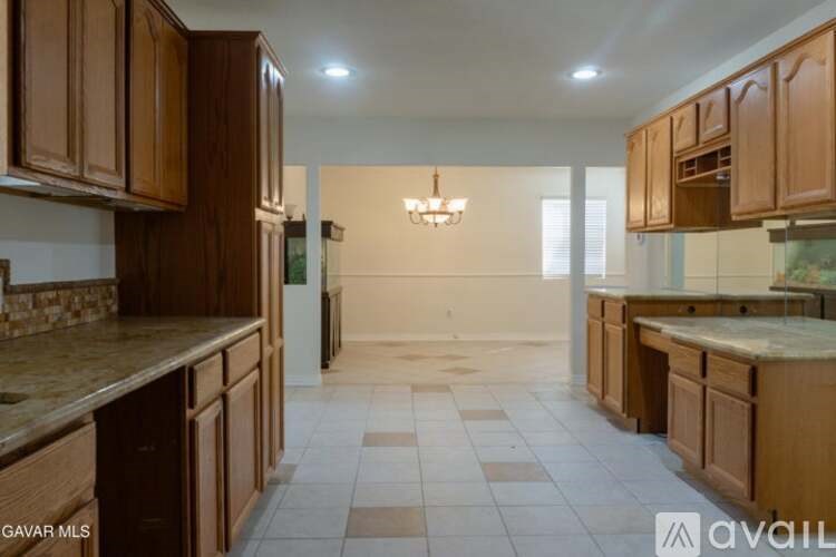 A kitchen with brown cabinets and a marble countertop.
