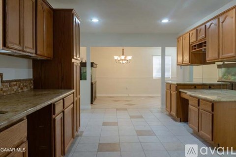 A kitchen with brown cabinets and a marble countertop.