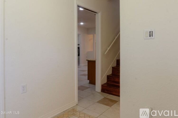 A hallway with a staircase and a doorway leading to another room.