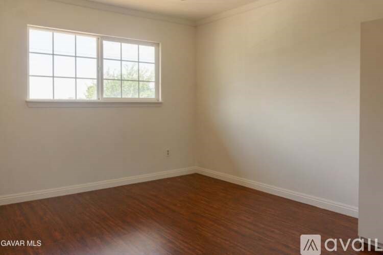 Empty room with a window and wooden flooring.