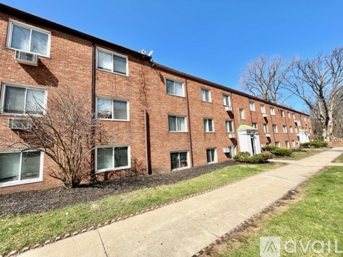 A row of red brick apartment buildings with a sidewalk in front.