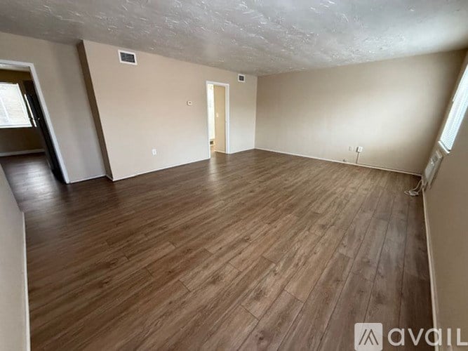 A room with wooden flooring and a door in the middle.