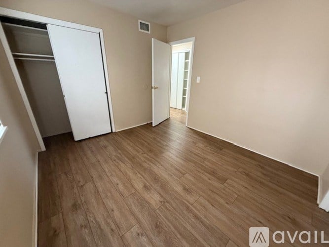 A room with wooden flooring and two doors, one of which is open.
