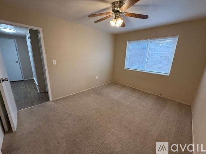 A room with a ceiling fan and a window with blinds.