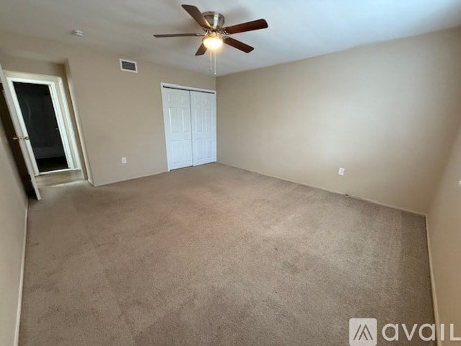 A room with a ceiling fan and carpeted floor.