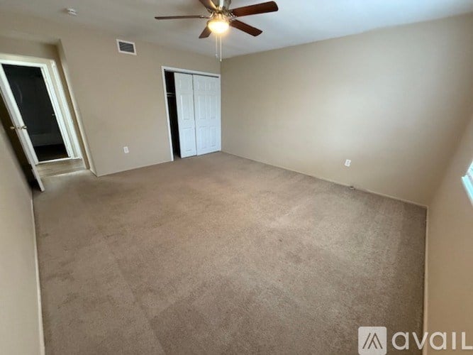 A room with a ceiling fan and carpeted floor.