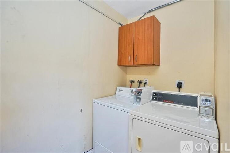 A small room with a washing machine and a cabinet above it.