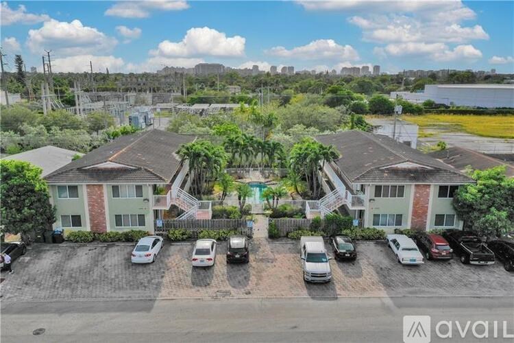 A parking lot with several cars in front of a building with a sign that reads "available".