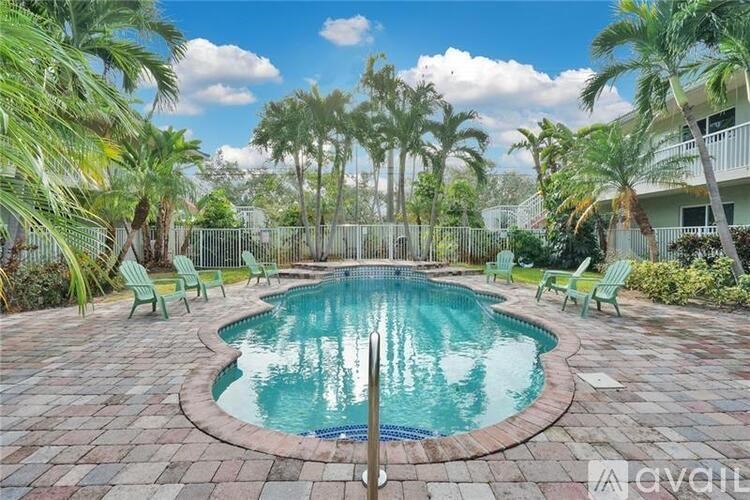 A pool surrounded by palm trees and lounge chairs.