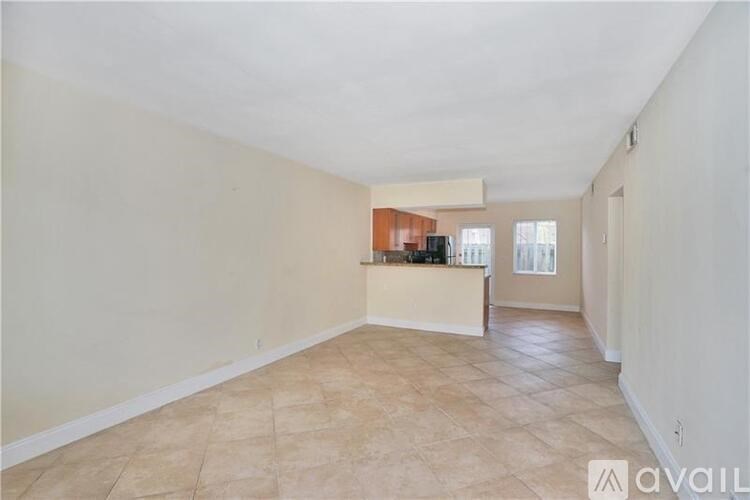 A spacious room with beige tiled flooring and white walls.