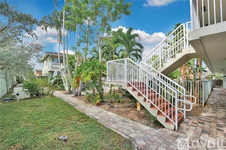 A white house with a staircase and a lawn.