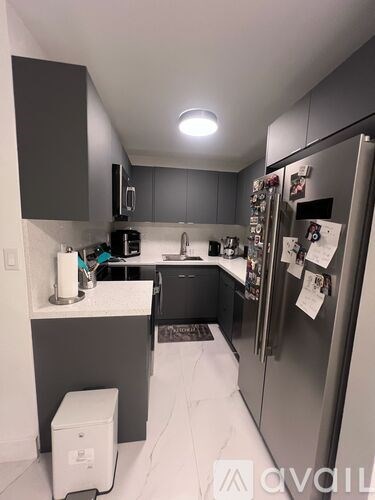 A kitchen with a refrigerator, sink, and cabinets.