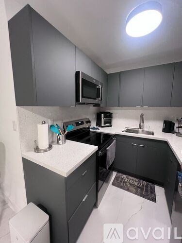 A modern kitchen with a white countertop and black cabinets.