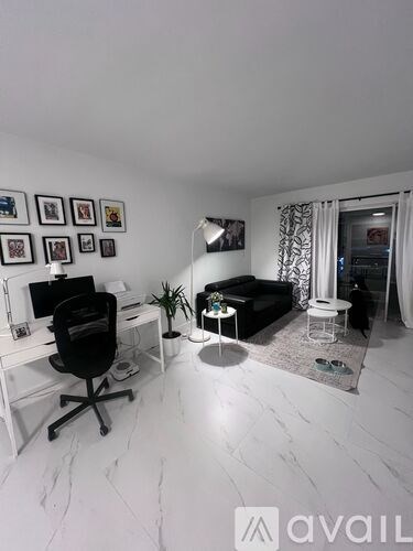 A white room with a black chair and a desk with a computer.