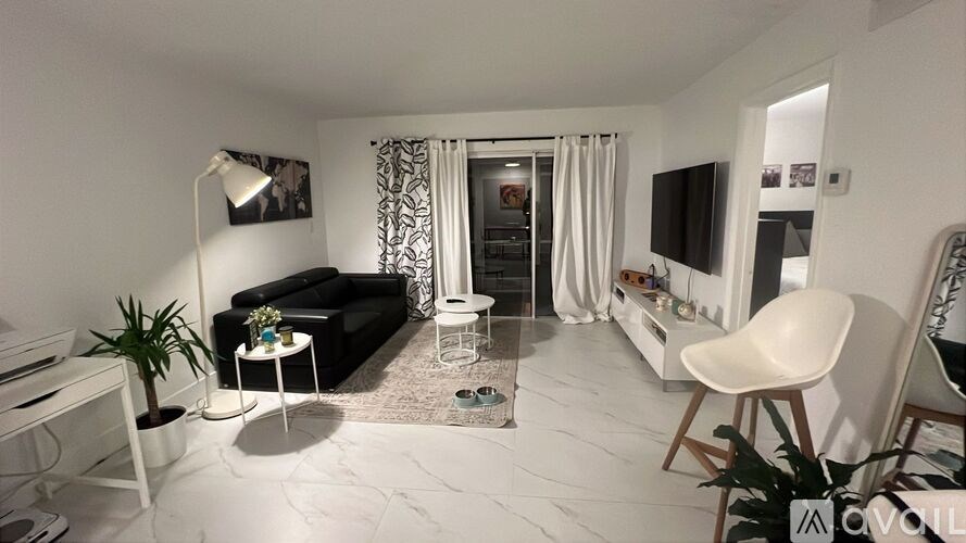 A living room with a black couch, a white chair, and a television.