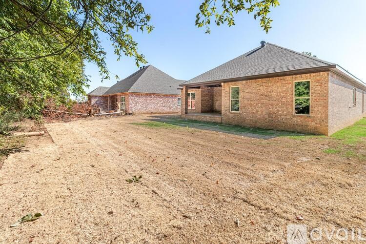 A house with a brown roof and brick walls is surrounded by a dirt field.