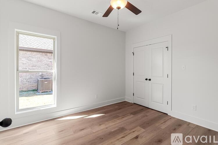A room with a ceiling fan and a window overlooking a backyard.