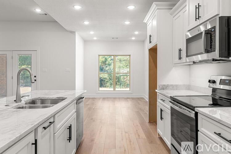A modern kitchen with white cabinets and a large window.