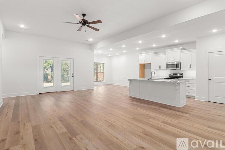 A spacious kitchen with wooden flooring and white walls.