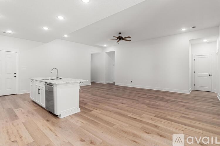 A kitchen island with a sink is in the middle of a room with wood flooring and white walls.
