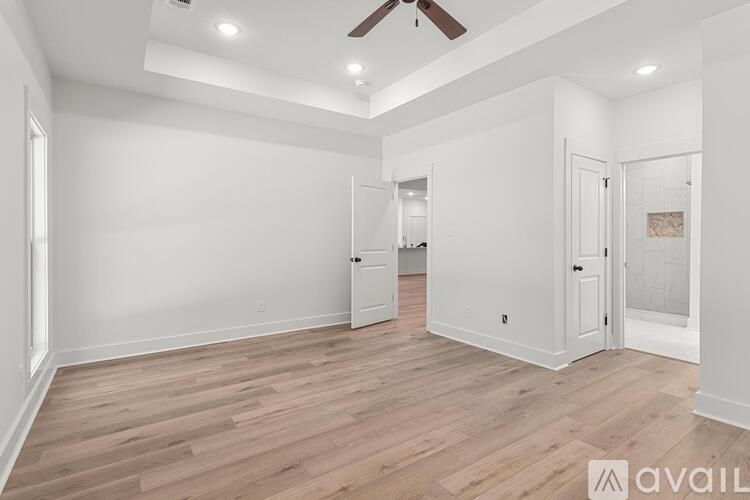 A spacious room with wooden flooring and a ceiling fan.