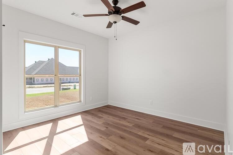 A room with a ceiling fan and a large window overlooking a building.