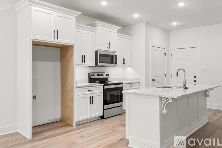 A kitchen with white cabinets and a wooden floor.