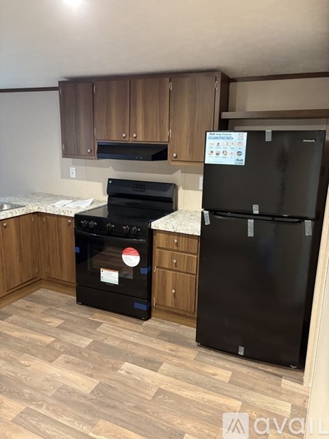 A kitchen with a black fridge and stove top oven.