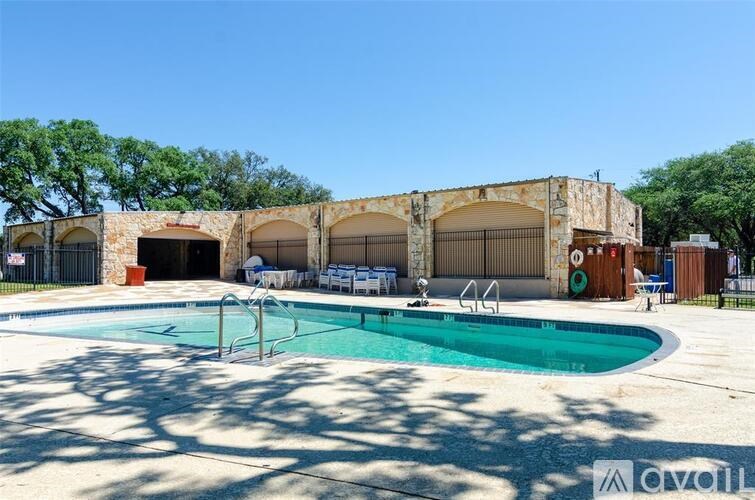 A pool area with a stone building and chairs.