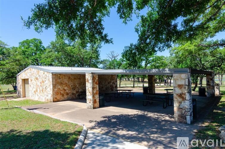 A stone building with a roof and pillars is surrounded by trees.