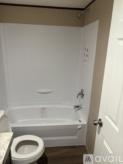 A white bathroom with a toilet, tub, and door.